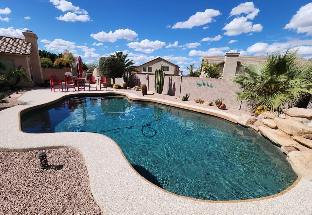 Backyard freeform pool with red patio chairs