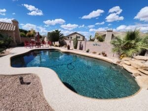 Backyard pool with red chairs and cacti