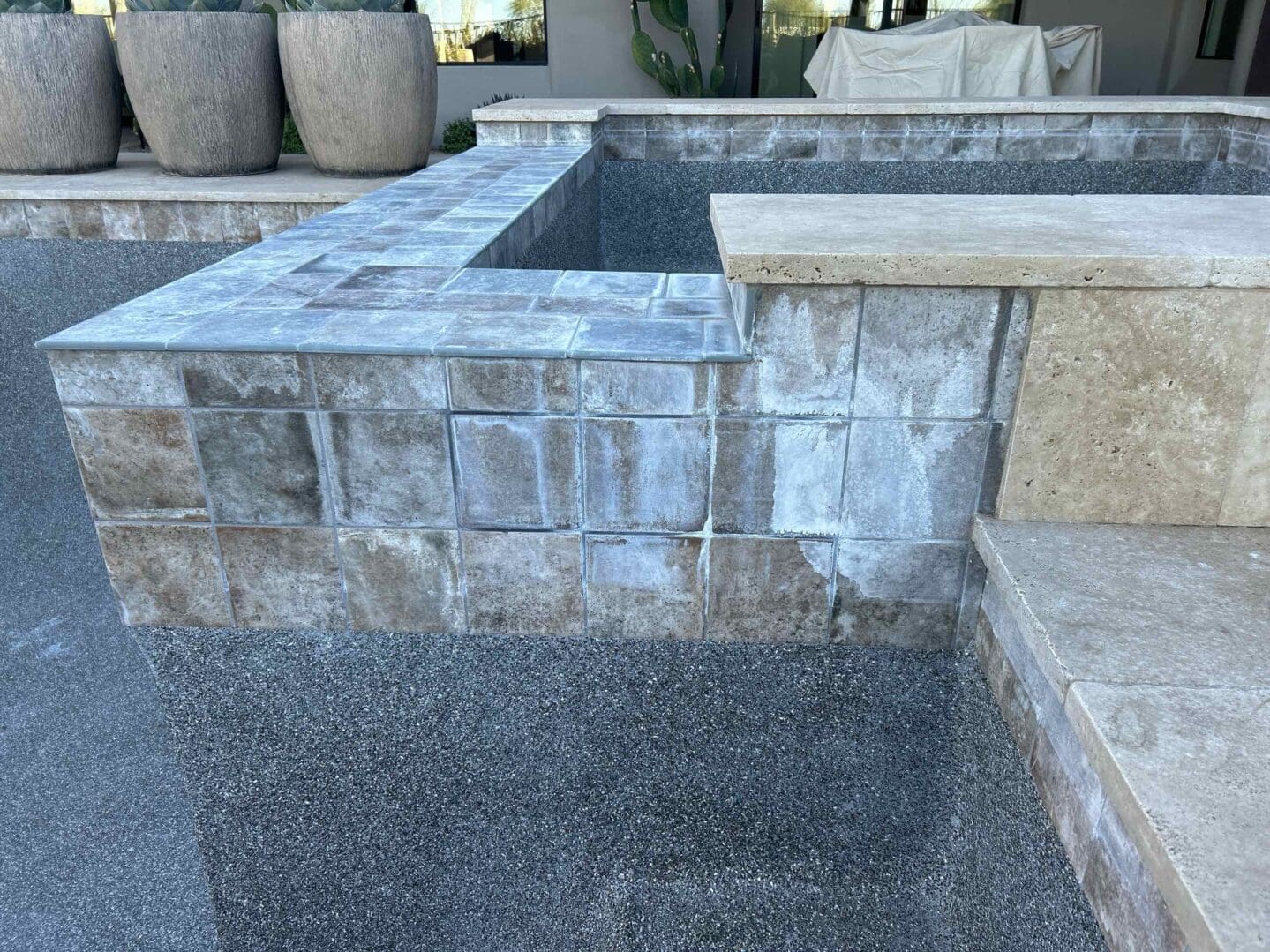 Stone-tiled pool edge with planters nearby.