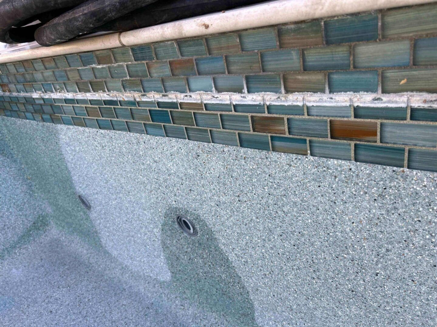 Pool tiles with green mosaic border design.
