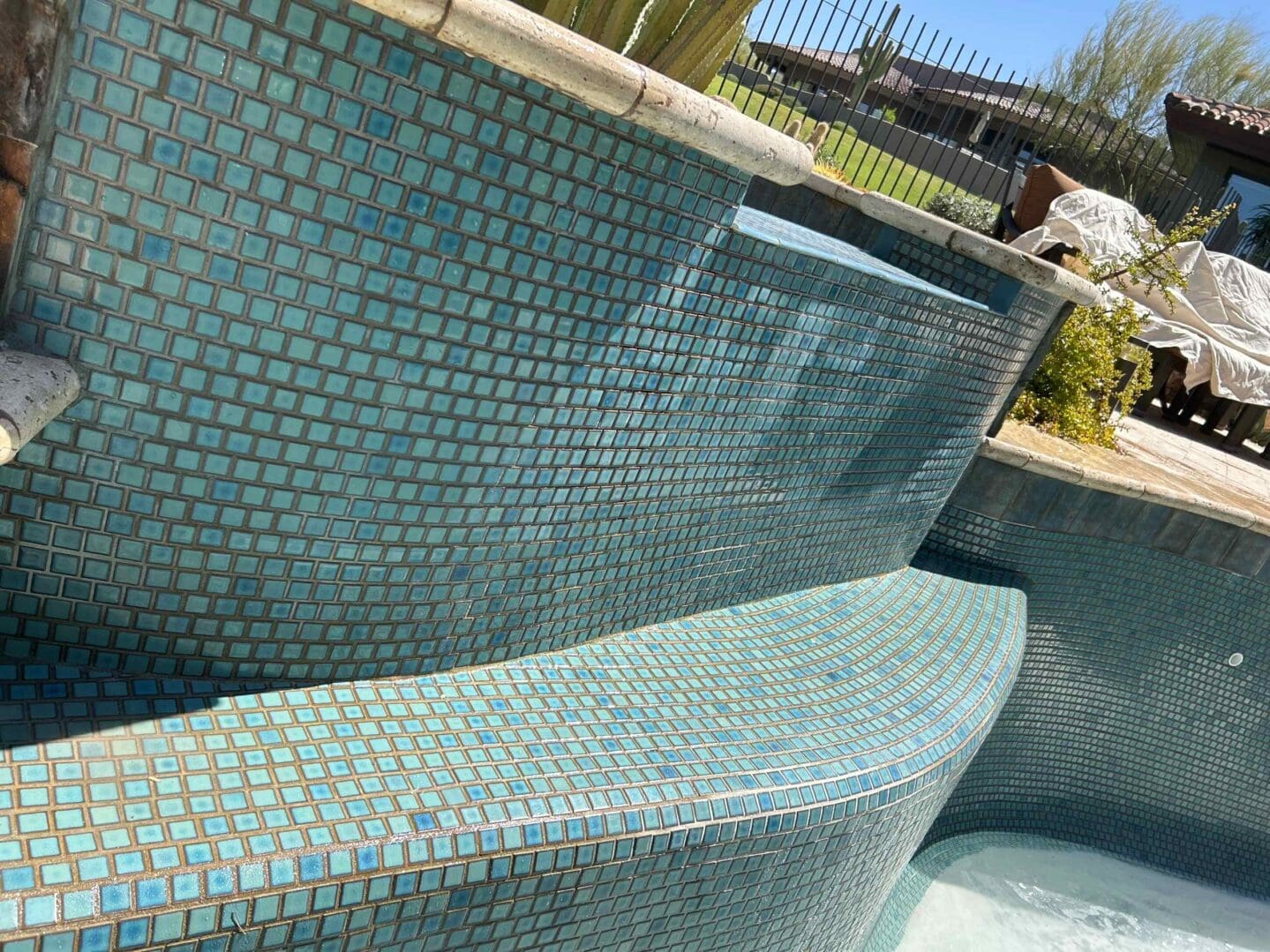 Blue-tiled outdoor pool with waterfall feature.