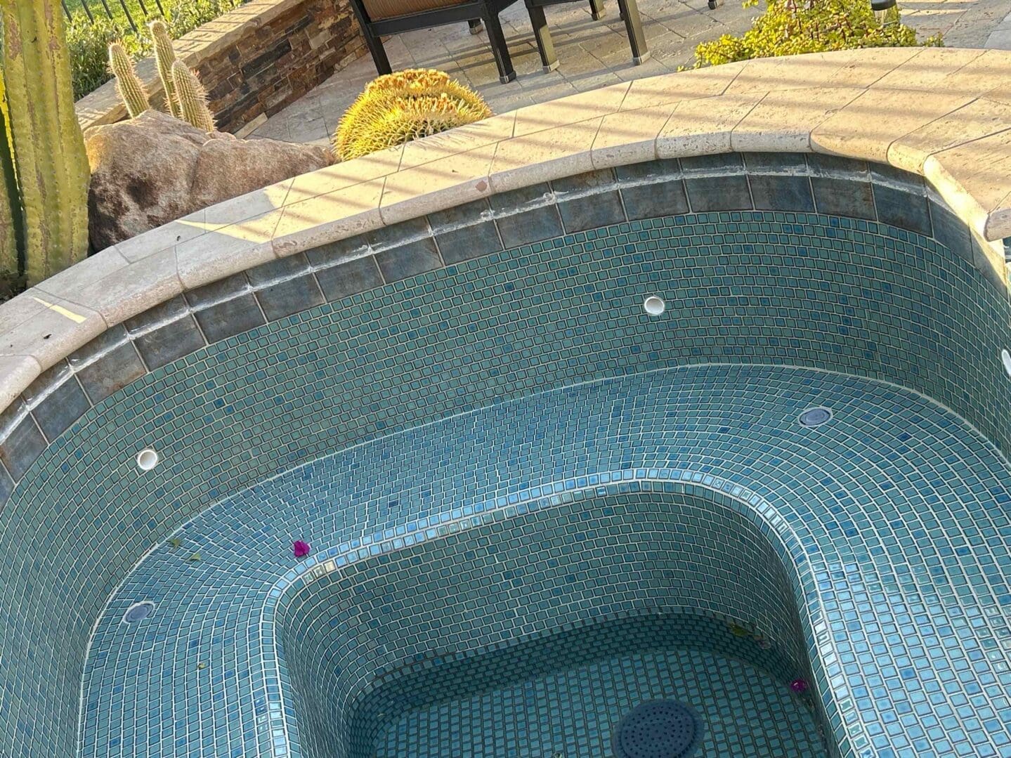 Empty tiled hot tub with surrounding patio.