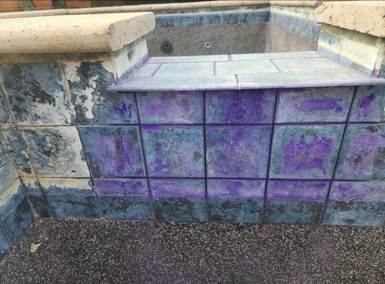 Purple-stained tiles around an empty pool.