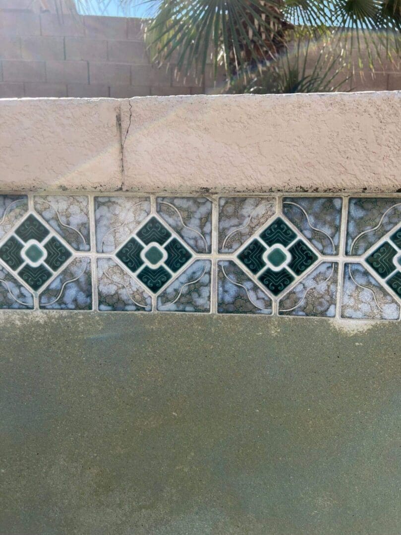 Pool wall with green and white tiles.